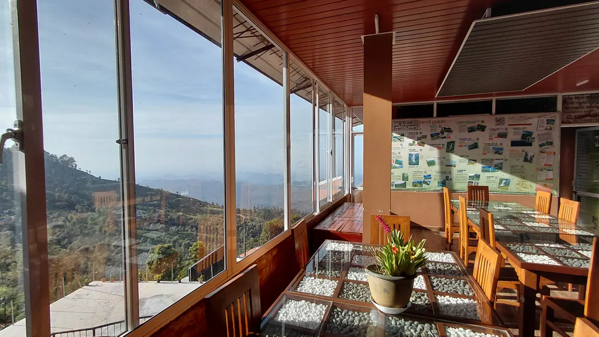 Dining room with large windows overlooking green hills.
