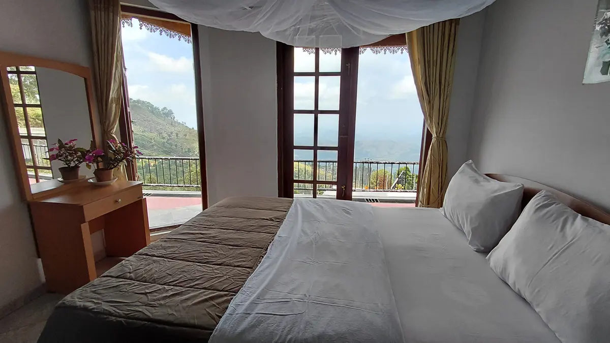 Guest room with a bed beside windows and a balcony door.
