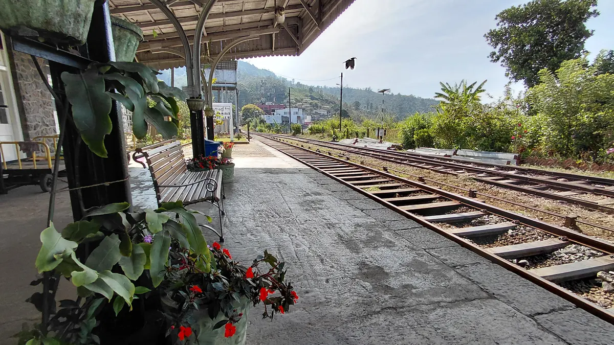 Railway platform and tracks with hills beyond.