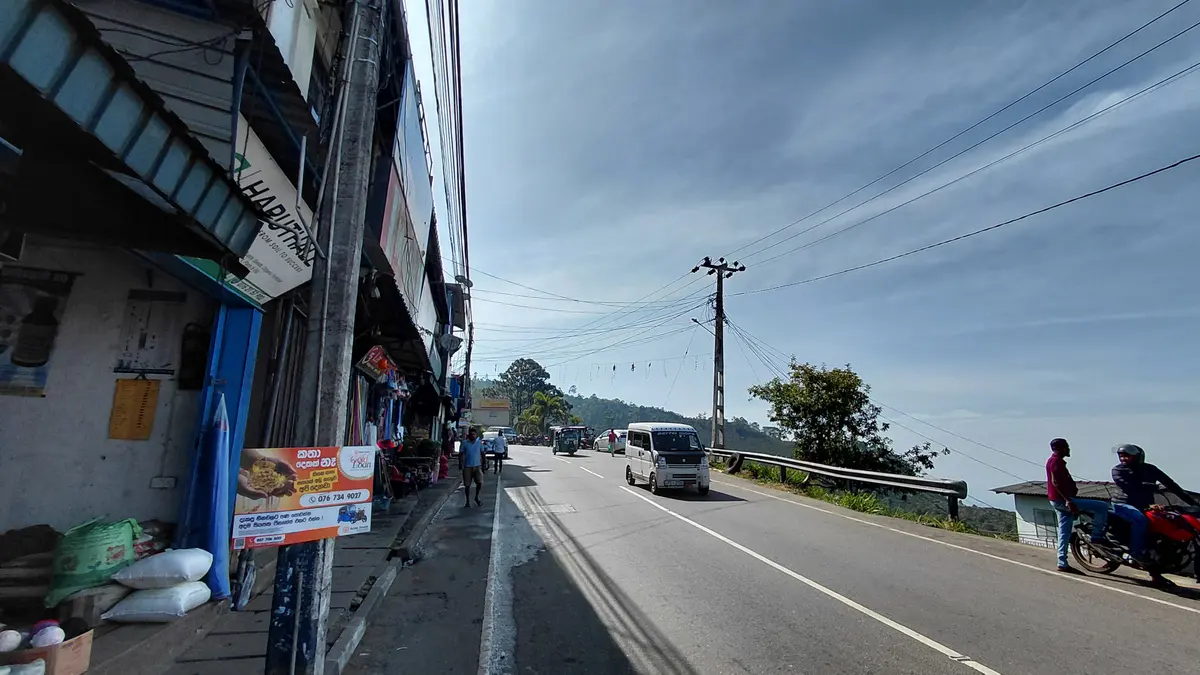 Street beside hillside buildings and distant mountains.